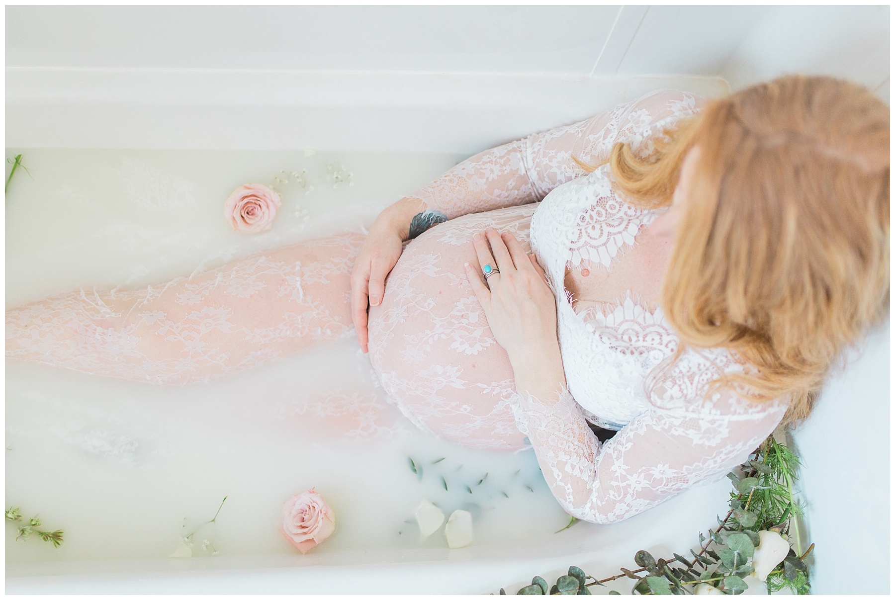 redheaded pregnant woman takes a milk bath with flowers in her bangor, maine, home in a white, see-through dress