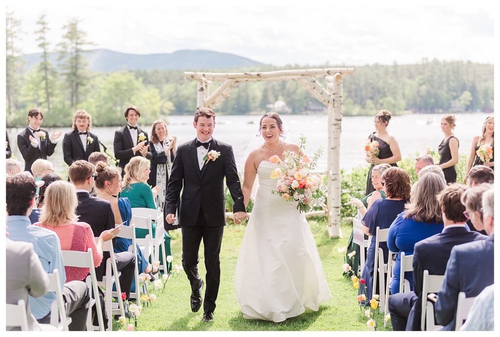 bride and groom get married at wedding venue tarry a while in bridgton maine. upscale luxury wedding with black tie groomsmen tuxes and black satin bridesmaid dresses, colorful flowers, summer maine wedding, lake, tent, outdoor dance floor, destination wedding