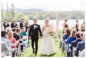 bride and groom get married at wedding venue tarry a while in bridgton maine. upscale luxury wedding with black tie groomsmen tuxes and black satin bridesmaid dresses, colorful flowers, summer maine wedding, lake, tent, outdoor dance floor, destination wedding