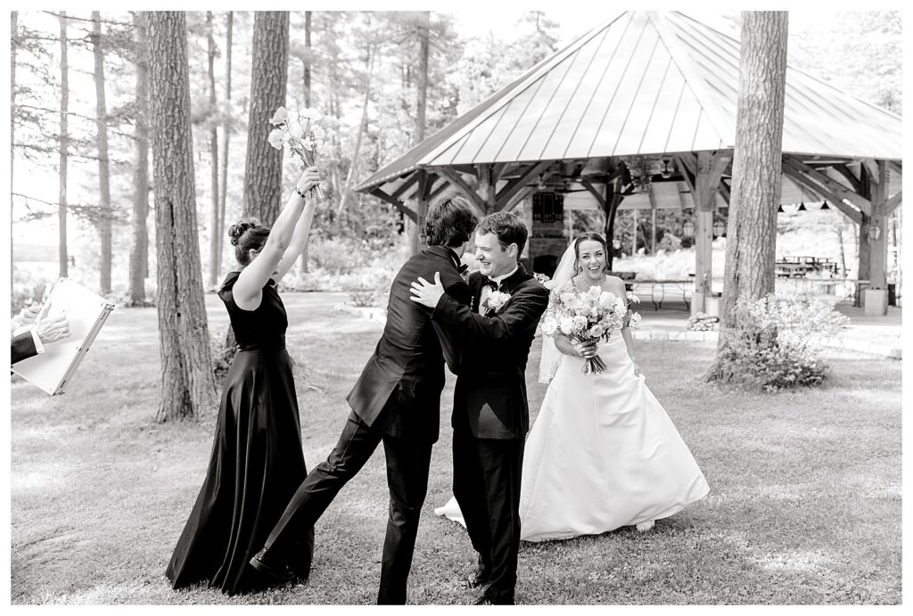 bride and groom get married at wedding venue tarry a while in bridgton maine. upscale luxury wedding with black tie groomsmen tuxes and black satin bridesmaid dresses, colorful flowers, summer maine wedding, lake, tent, outdoor dance floor, destination wedding