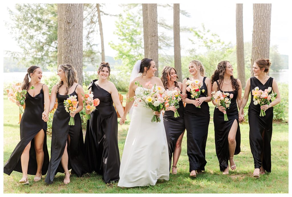 bride and groom get married at wedding venue tarry a while in bridgton maine. upscale luxury wedding with black tie groomsmen tuxes and black satin bridesmaid dresses, colorful flowers, summer maine wedding, lake, tent, outdoor dance floor, destination wedding