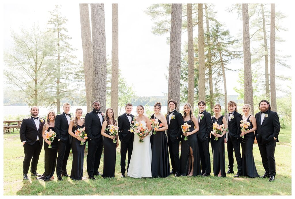 bride and groom get married at wedding venue tarry a while in bridgton maine. upscale luxury wedding with black tie groomsmen tuxes and black satin bridesmaid dresses, colorful flowers, summer maine wedding, lake, tent, outdoor dance floor, destination wedding