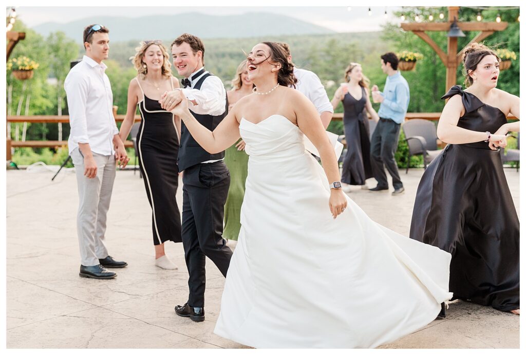 bride and groom get married at wedding venue tarry a while in bridgton maine. upscale luxury wedding with black tie groomsmen tuxes and black satin bridesmaid dresses, colorful flowers, summer maine wedding, lake, tent, outdoor dance floor, destination wedding